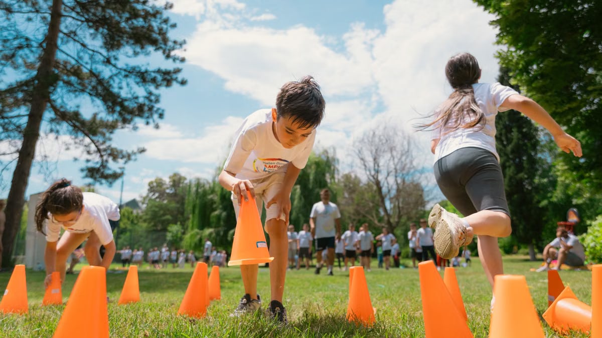 Children playing an obstacle course in a park on a sunny day, promoting fun and physical fitness.